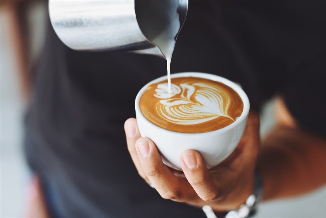 A barista pours coffee into a mug.