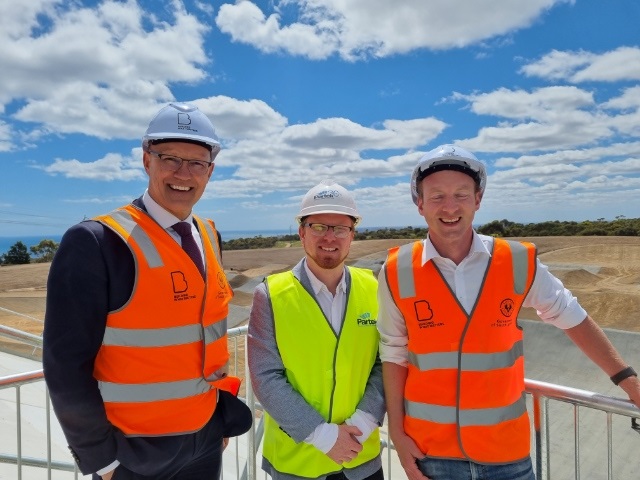 Minister for Recreation, Sport and Racing Corey Wingard; City of Onkaparinga Deputy Mayor Simon McMahon; and Environment Minister David Speirs smile in front of the under-construction Sam Willoughby BMX Facility.