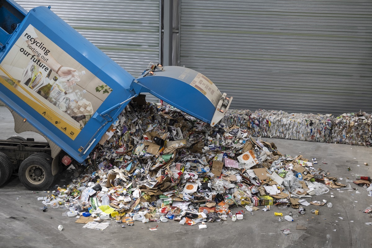 A blue recycling truck unloads its contents at the new SMRF.