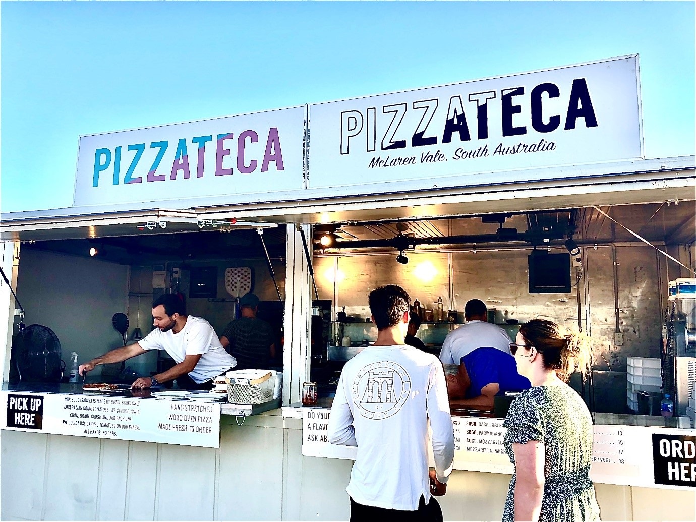 The front of the Pizzateca pop up at Aldinga Beach, with customers waiting to order and a chef preparing a pizza.