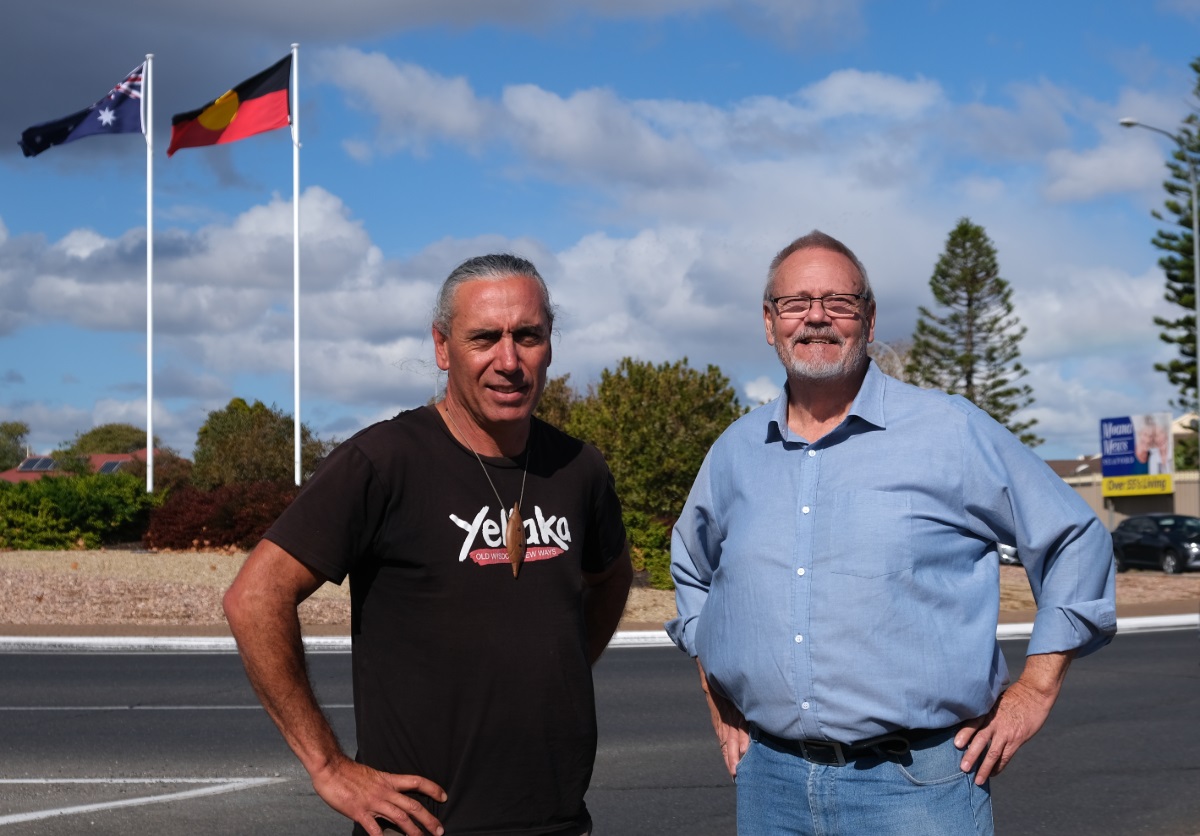 Karl Telfer with Councillor Richard Peat at the Seaford roundabout in front of the new Aboriginal flag.
