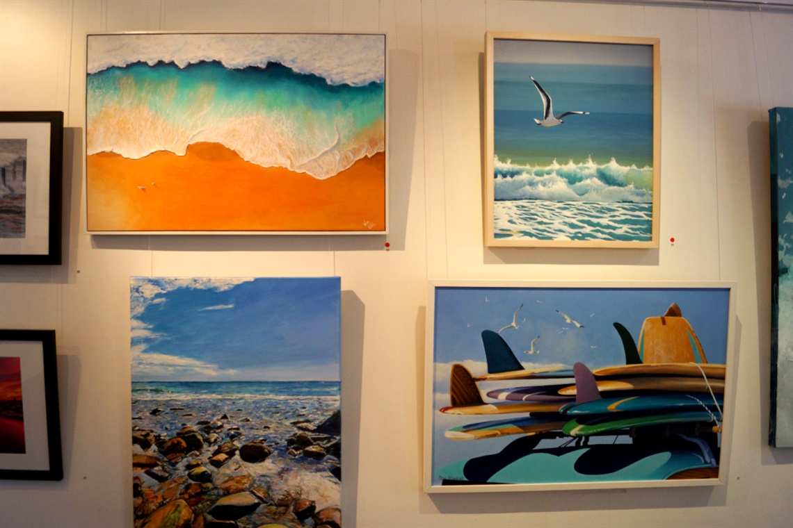 Framed paintings of surfing scenes on the wall of the Arts Centre.