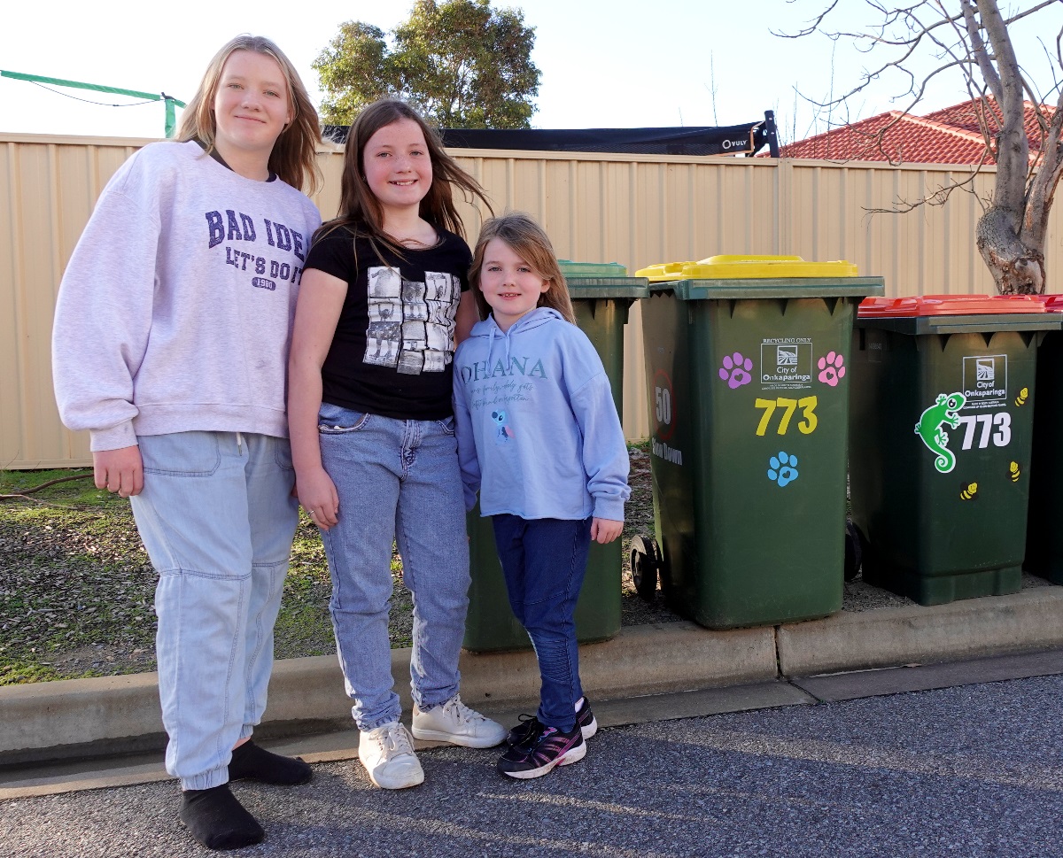 Sisters Mikayla, Alexa and Indy alongside some bins covered with colourful stickers.