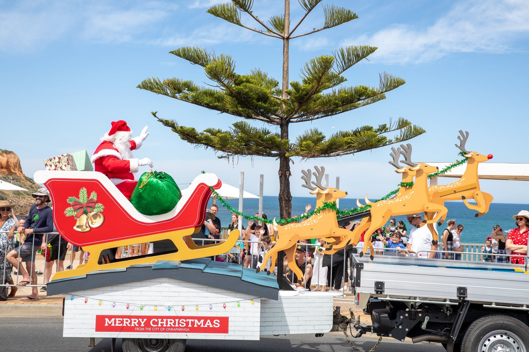 Santa Claus waves to the crowd in his sleigh being pulled on the back of a ute on the Esplanade at Christies Beach.