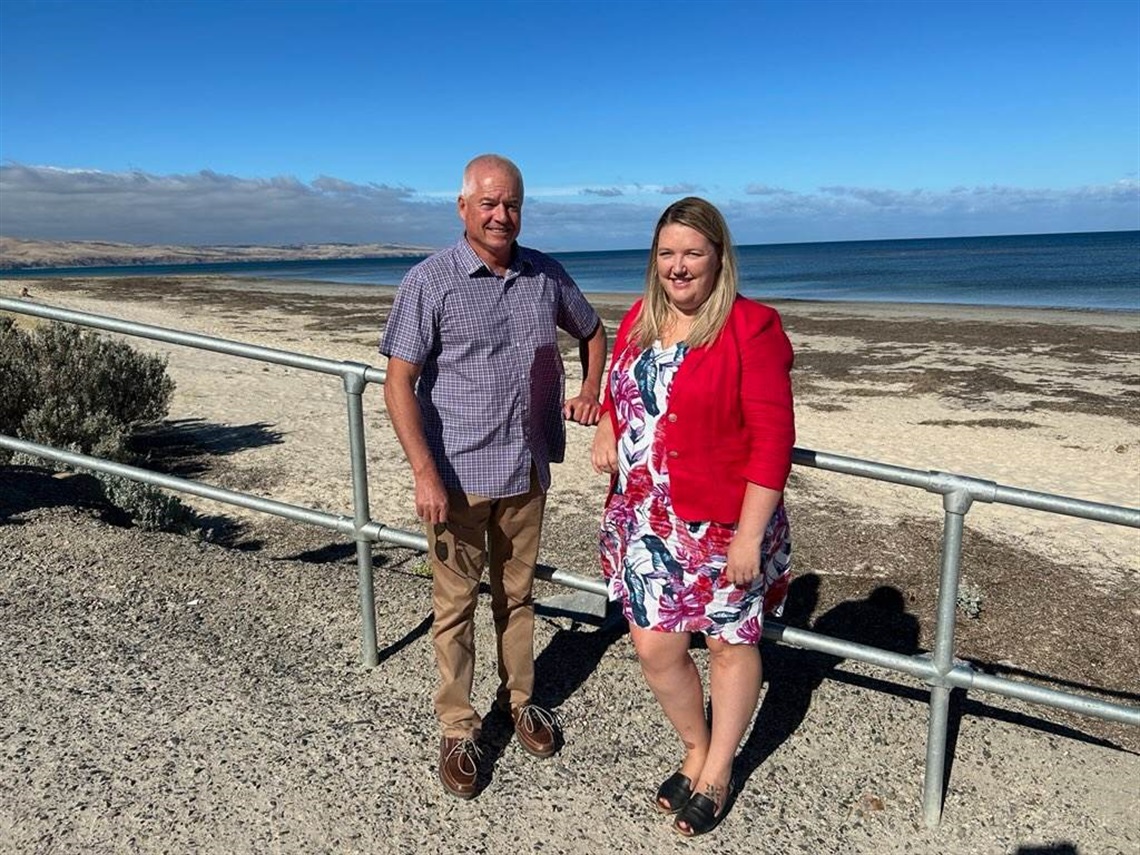 Councillors Michael Yeomans and Lauren Jew smile and lean on a ramp's railing on the foreshore.