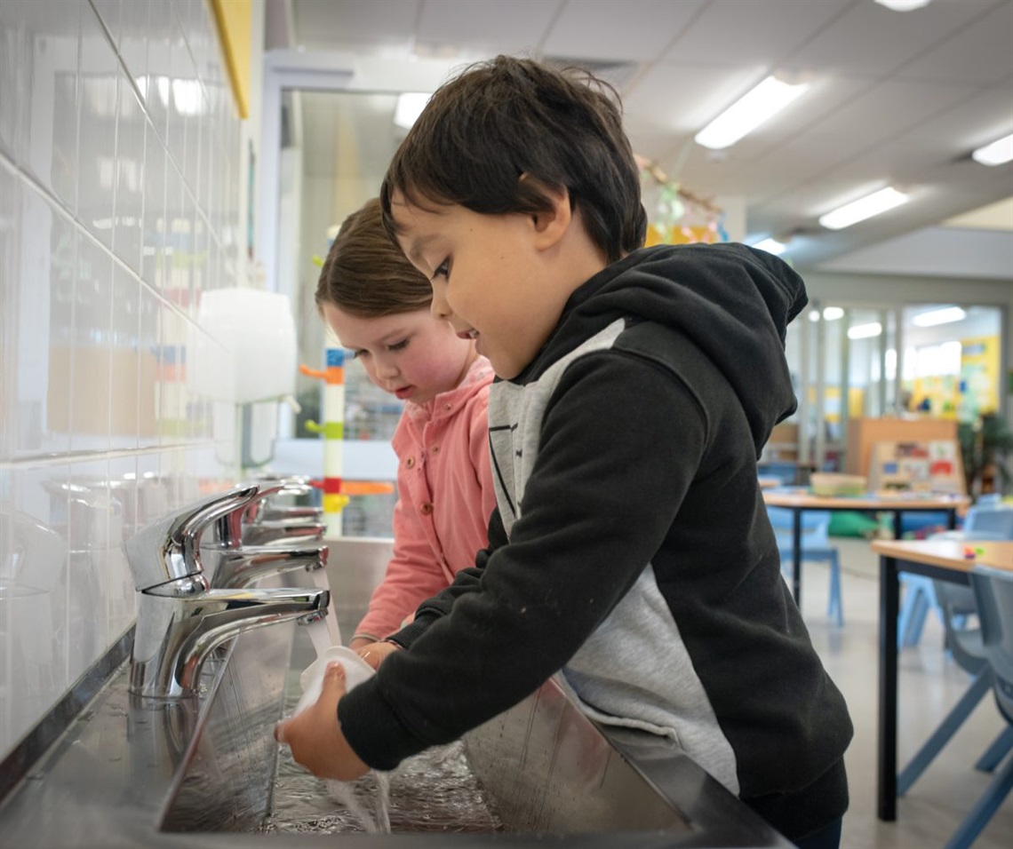 Marlia and Gede wash yoghurt containers to prepare them for a new life as point pot holders.