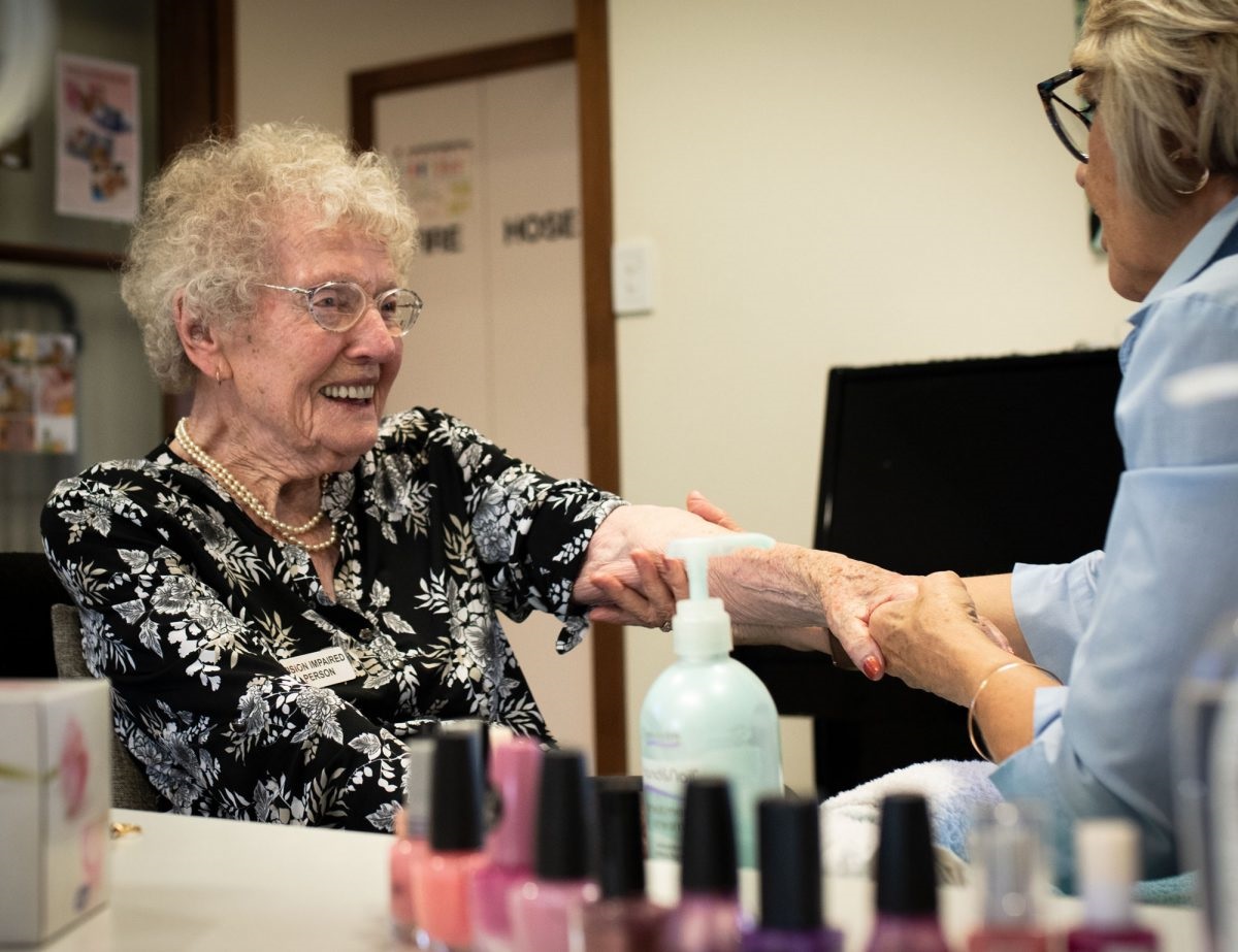 Kathleen enjoys a manicure from volunteer Loraine Thompson.