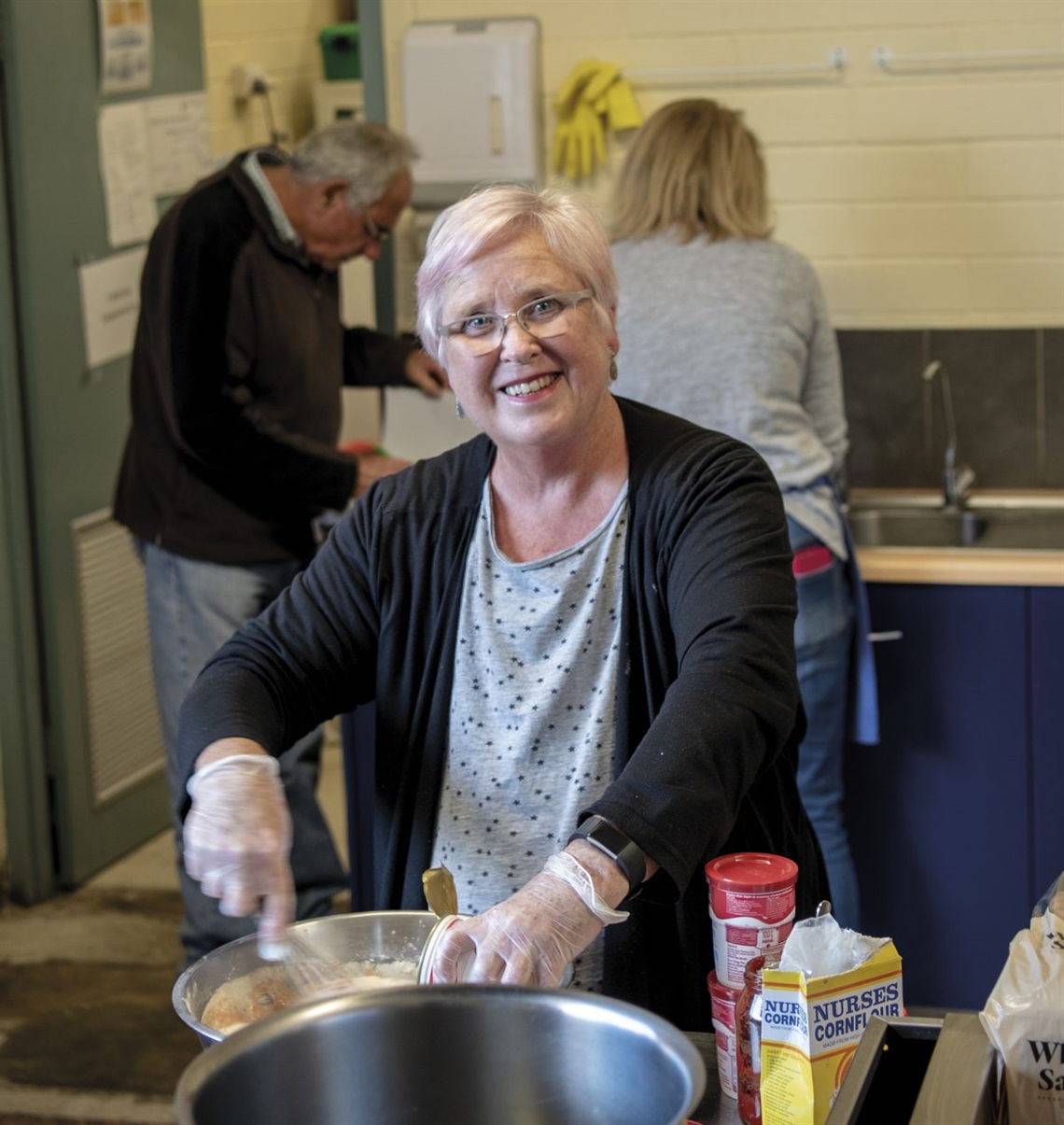 Mary Dittmar helps prepare dinner for people experiencing hardship; take-home sandwiches; Peter Sheerat, Tracy Harper and Helen Telford cook up a storm with other volunteers.