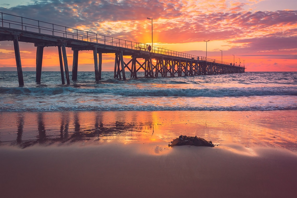 The view of Port Noarlunga jetty from the beach at sunset.