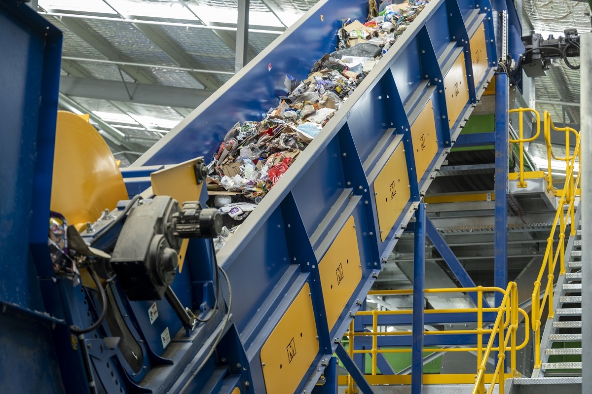 High-tech machinery carries recyclables up a blue conveyor belt.