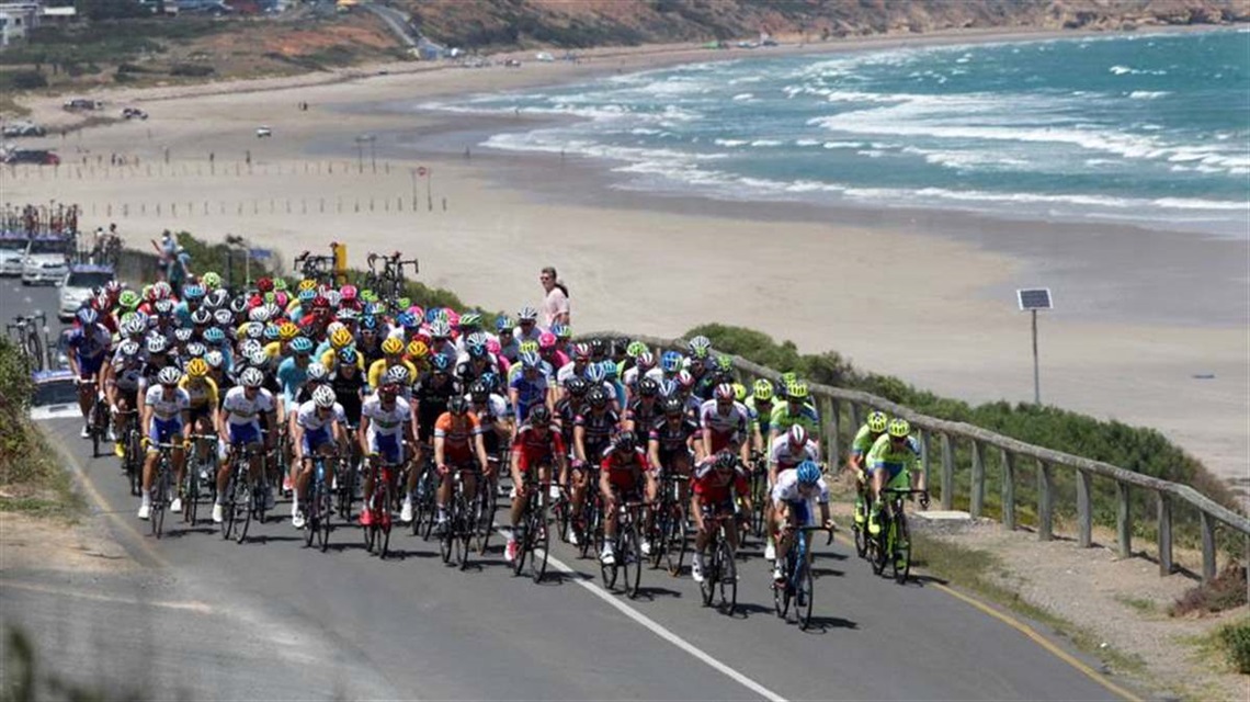 Cyclists in a large pack race along a coastal road at Aldinga.