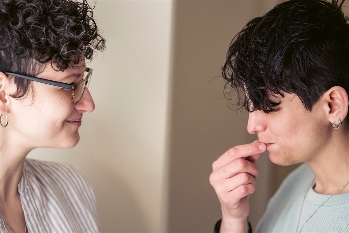 A close-up of two women smiling at each other while in discussion.