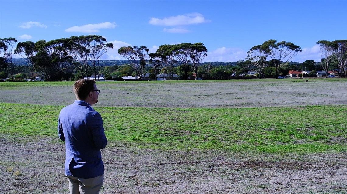 City of Onkaparinga Acting Mayor Simon McMahon looks out towards the grassy Knox Park on a blue-sky day fringed by gum trees.