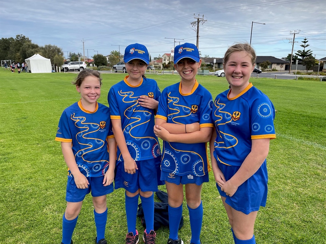 Under 12 representatives from the Seacombe Tigers Softball Club smile in their blue uniforms a grassy softball field.