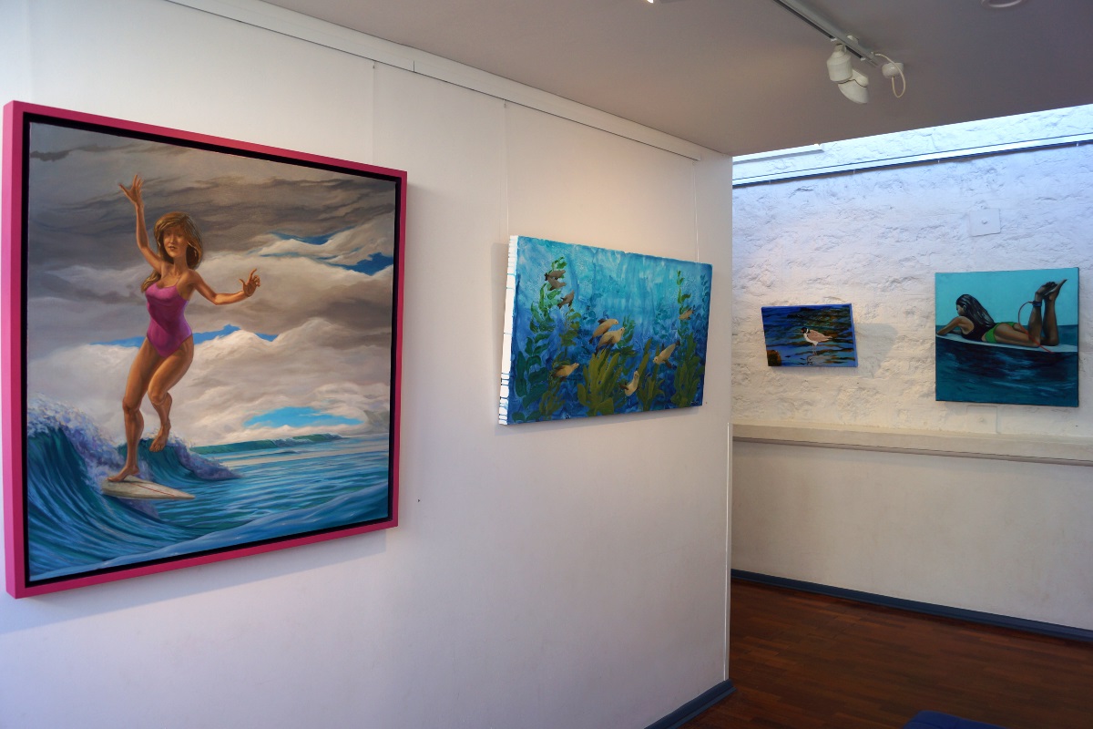 Framed paintings of surfing scenes on the wall of the Arts Centre.