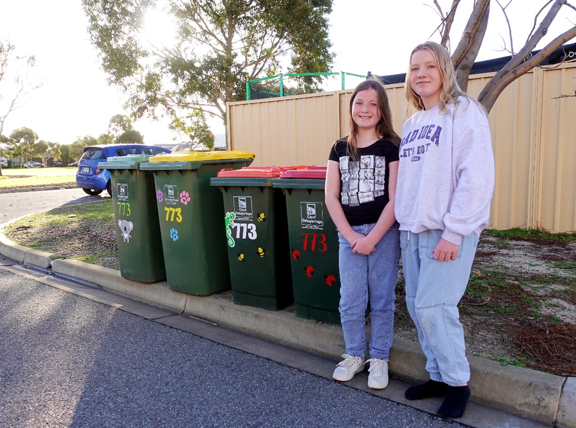 Alexa and sister Mikayla alongside bins covered with stickers.