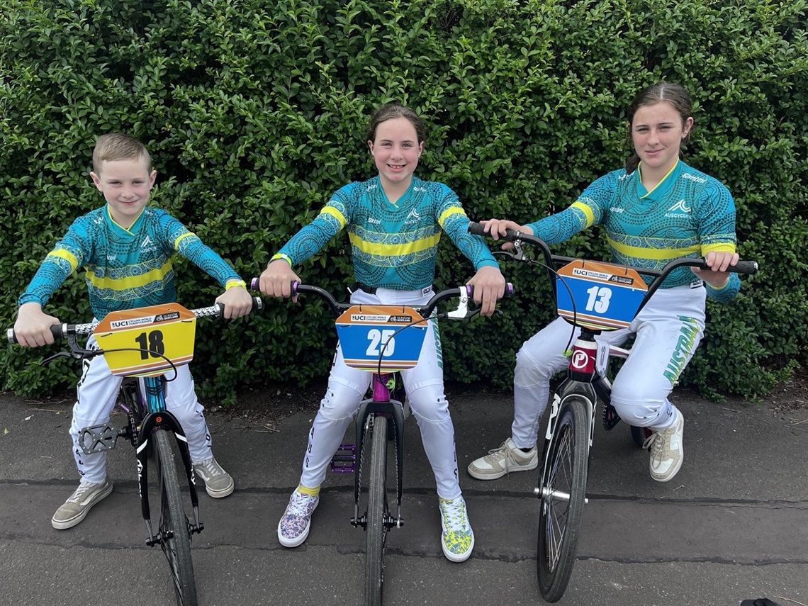 Happy Valley's Lars, Penelope and Isabella Blackwell smiling on their BMX bikes in Australian team uniforms.