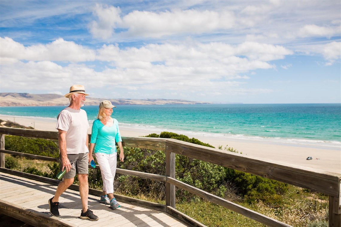 Photo of two people walking along a boardwalk at the beach