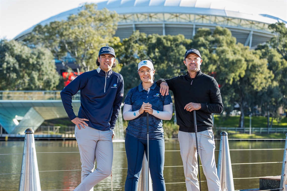 Three golfers smile alongside the River Torrens in Adelaide.