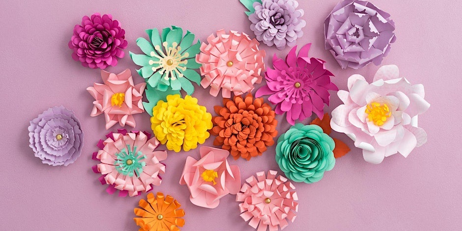 A selection of colourful paper flowers atop a light pink background.