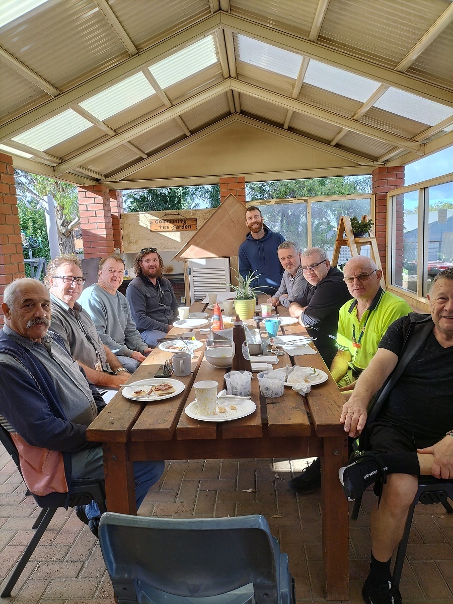 Smiling men sit around a table for a men's breakfast.