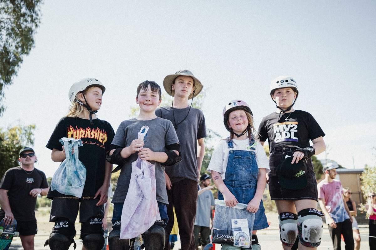 A group of young smiling skateboarders huddle together.