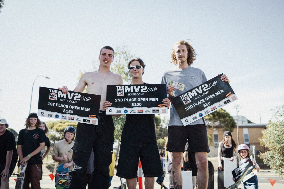 Three open men's skateboarders pose for the camera with their awards.