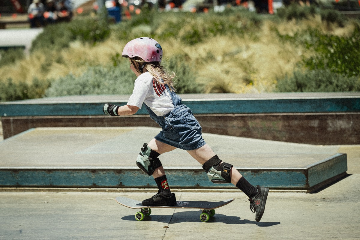 A young girl skater glides along the skate park.