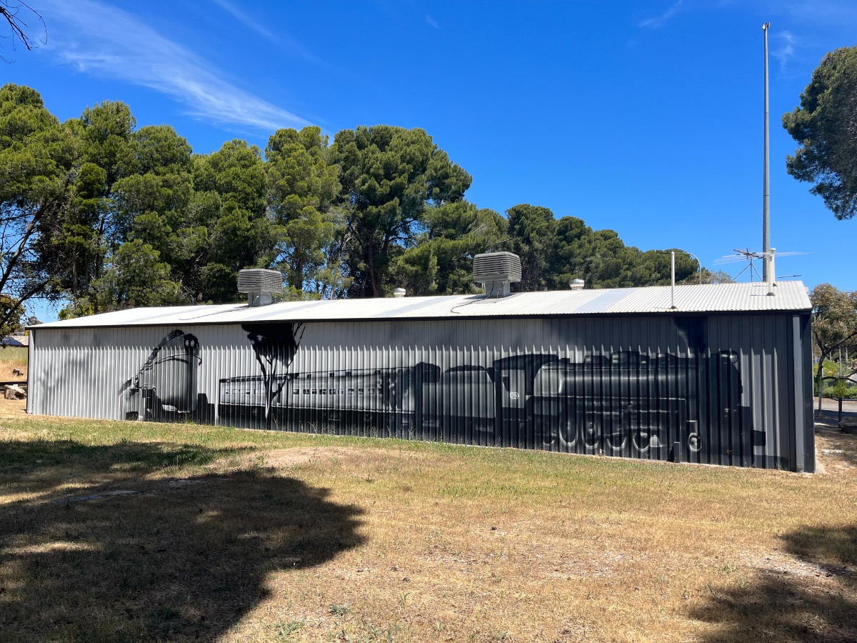 A mural featuring a locomotive on the side of the Noarlunga Model Railroaders Inc. building.
