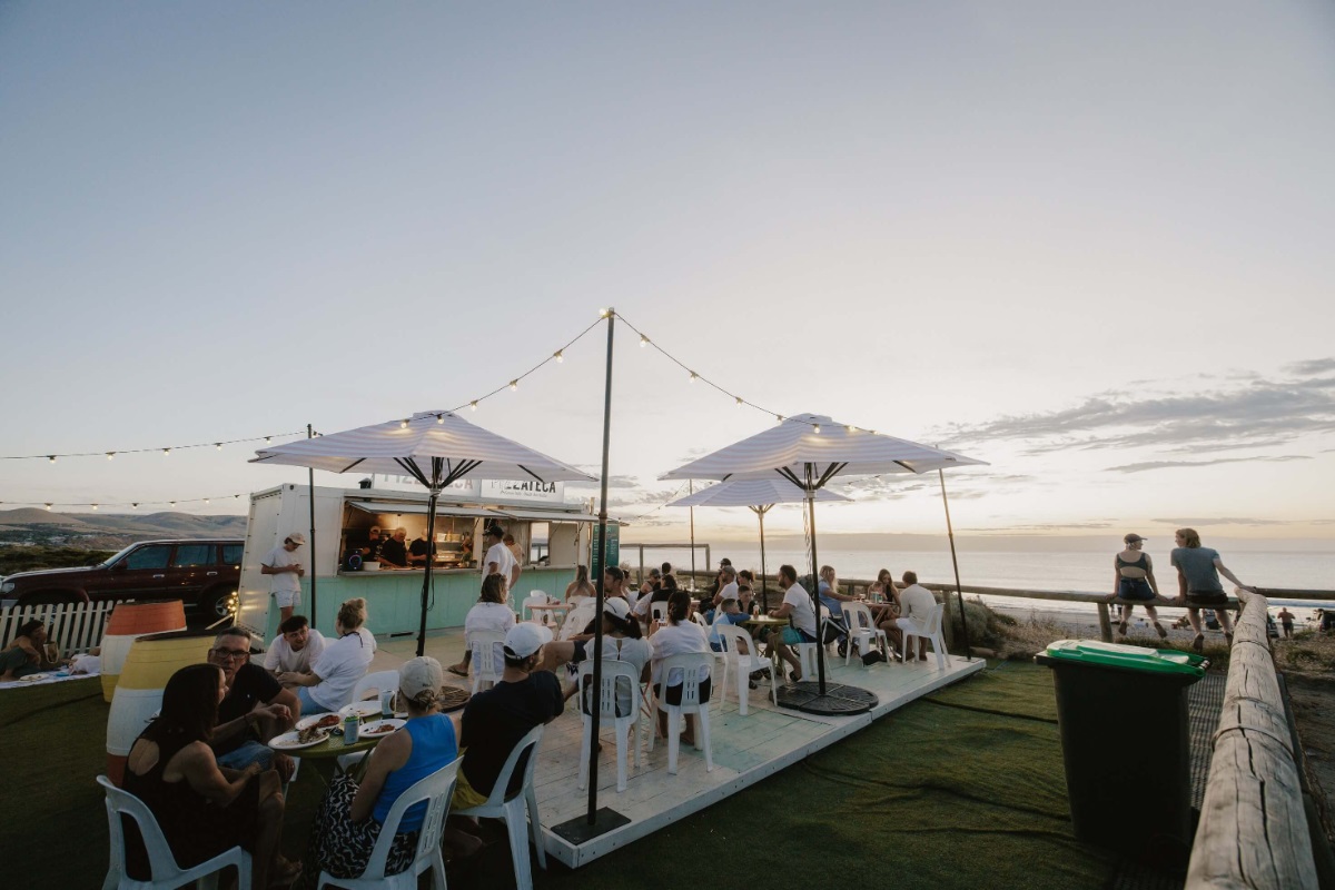 A pop-up pizzeria alongside the beach with dinners eating dinner alfresco.