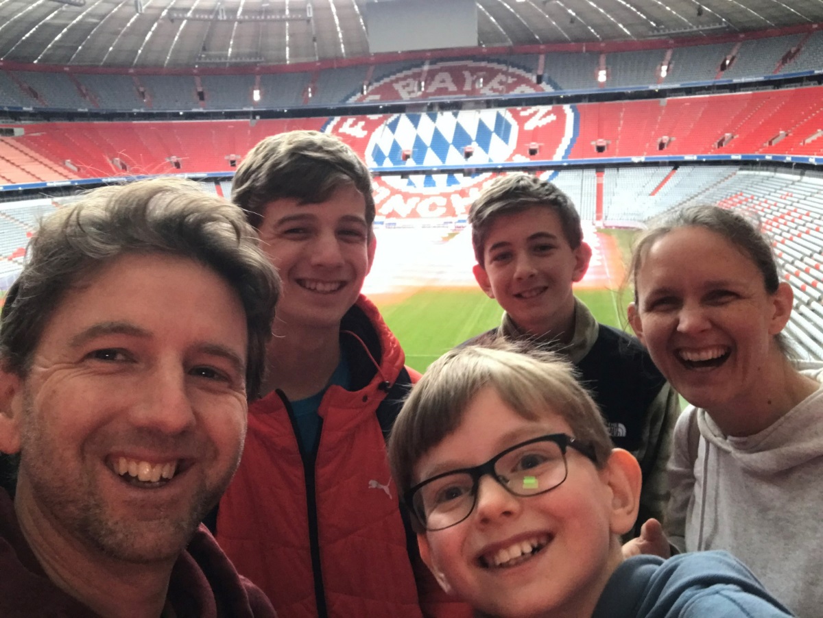 Jordan Pritchard, his three sons and wife, pose inside a European soccer stadium.