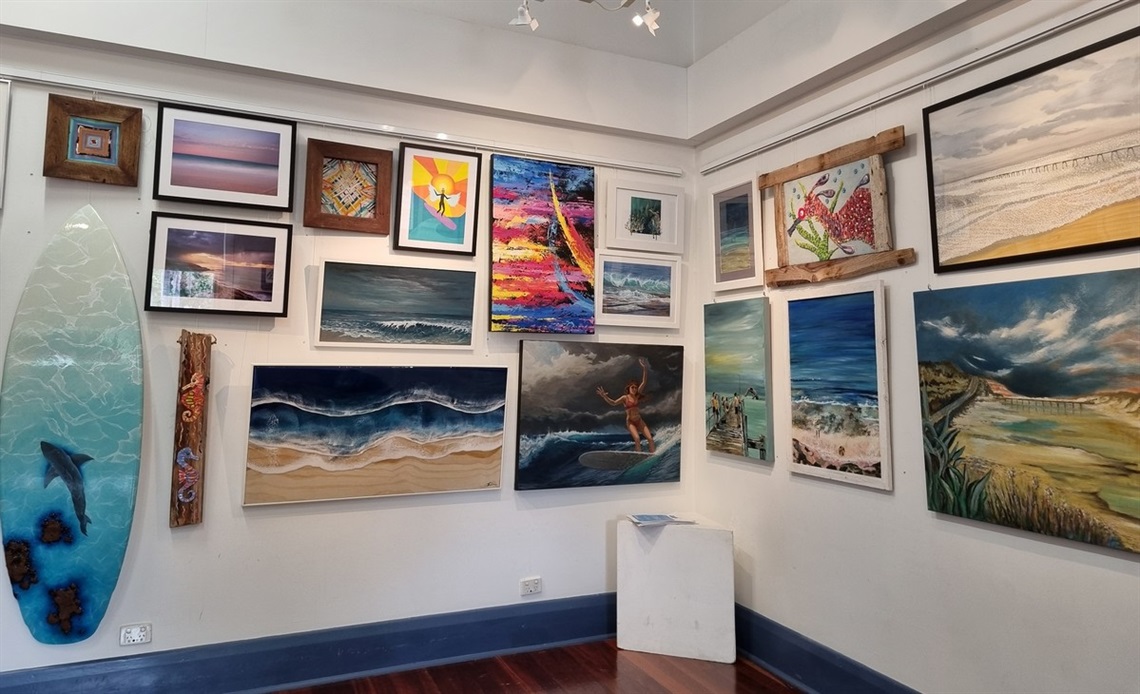 A photo of two walls covered in surf-themed art inside the Port Noarlunga Arts Centre at the 2022 Surf Art exhibition.