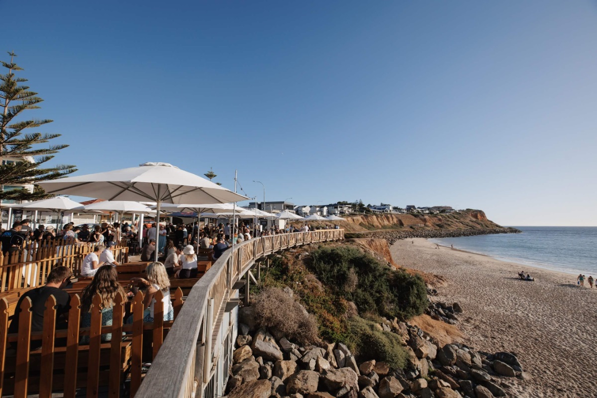 The coastline at Christies Beach with umbrellas and patrons dining at the SandBAR.