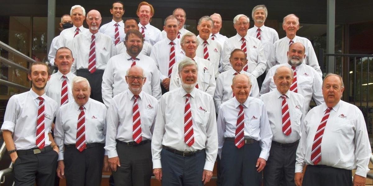 The famous Adelaide Male Voice Choir pose for a photograph in their white shirts and red ties.