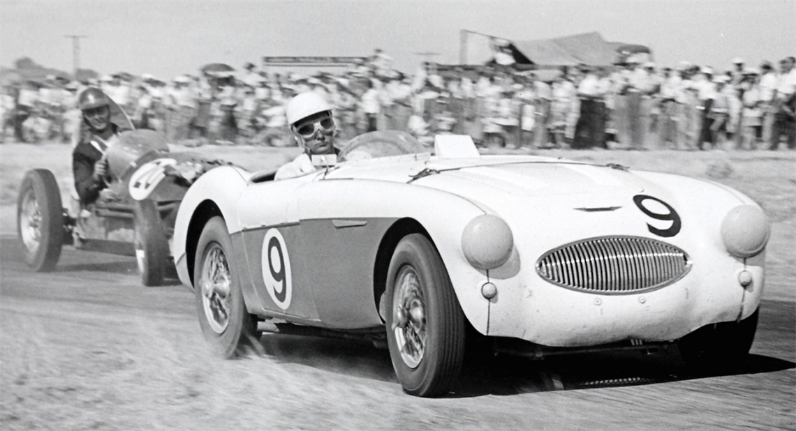 Willunga racing driver, Jim Goldfinch, in a black-and-white 1959 photo driving a white racing car with the number 9 on it in front of crowds of spectators.