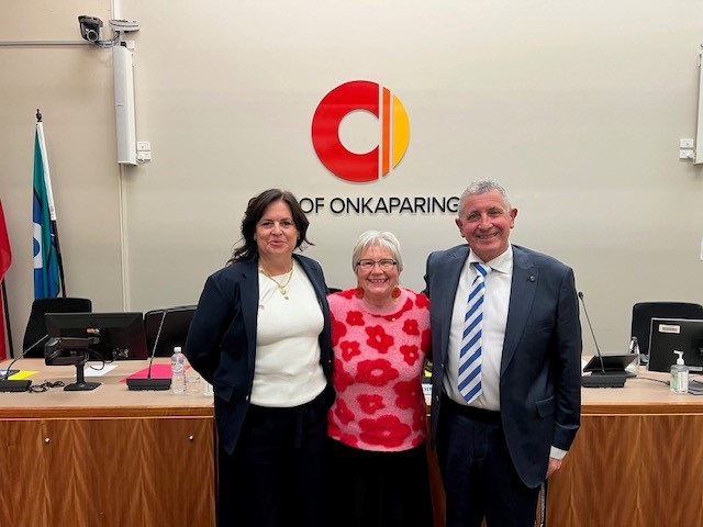 Councillor Kim Davis stands alongside Mayor Moira Were and Pimpala councillor Michael Fisher in the Council chamber with the City of Onkaparinga logo behind them.