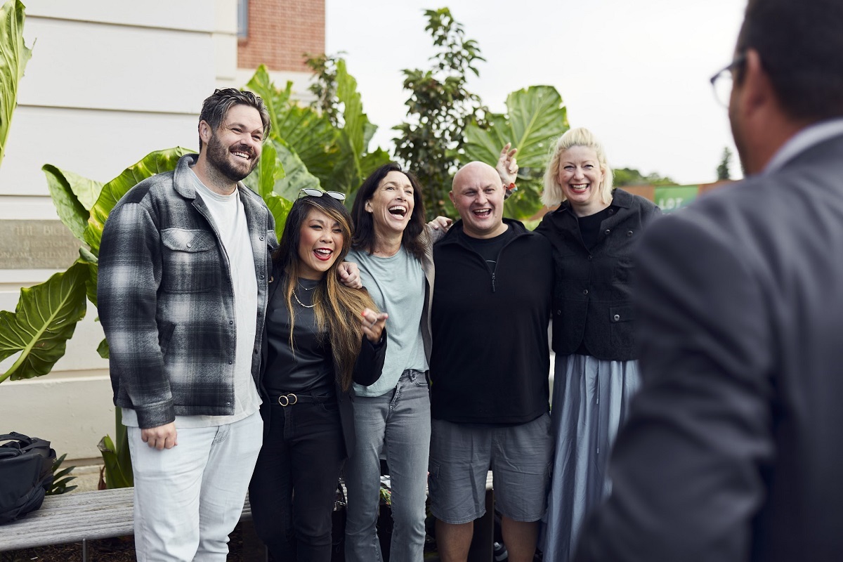 A group of smiling eventgoers link arms and pose for a photo.