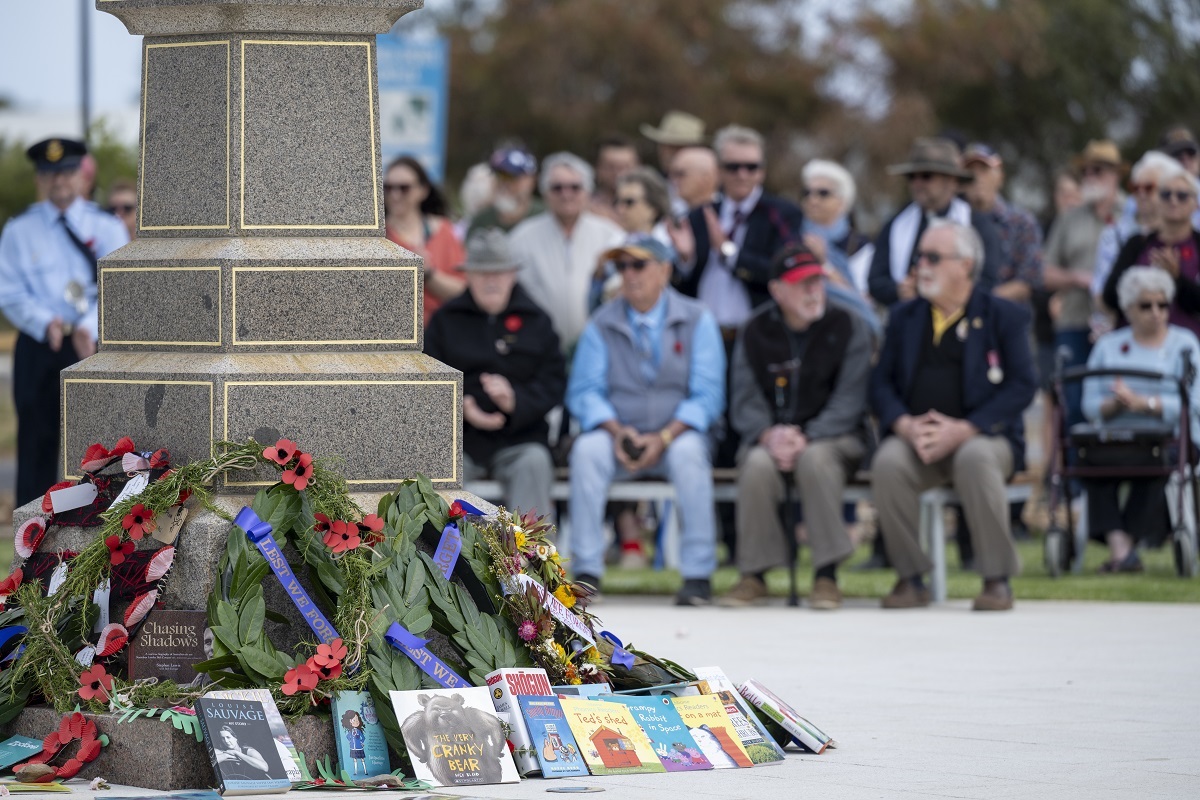 Wreaths and donated books rest against the side of the Aldinga War Memorial.