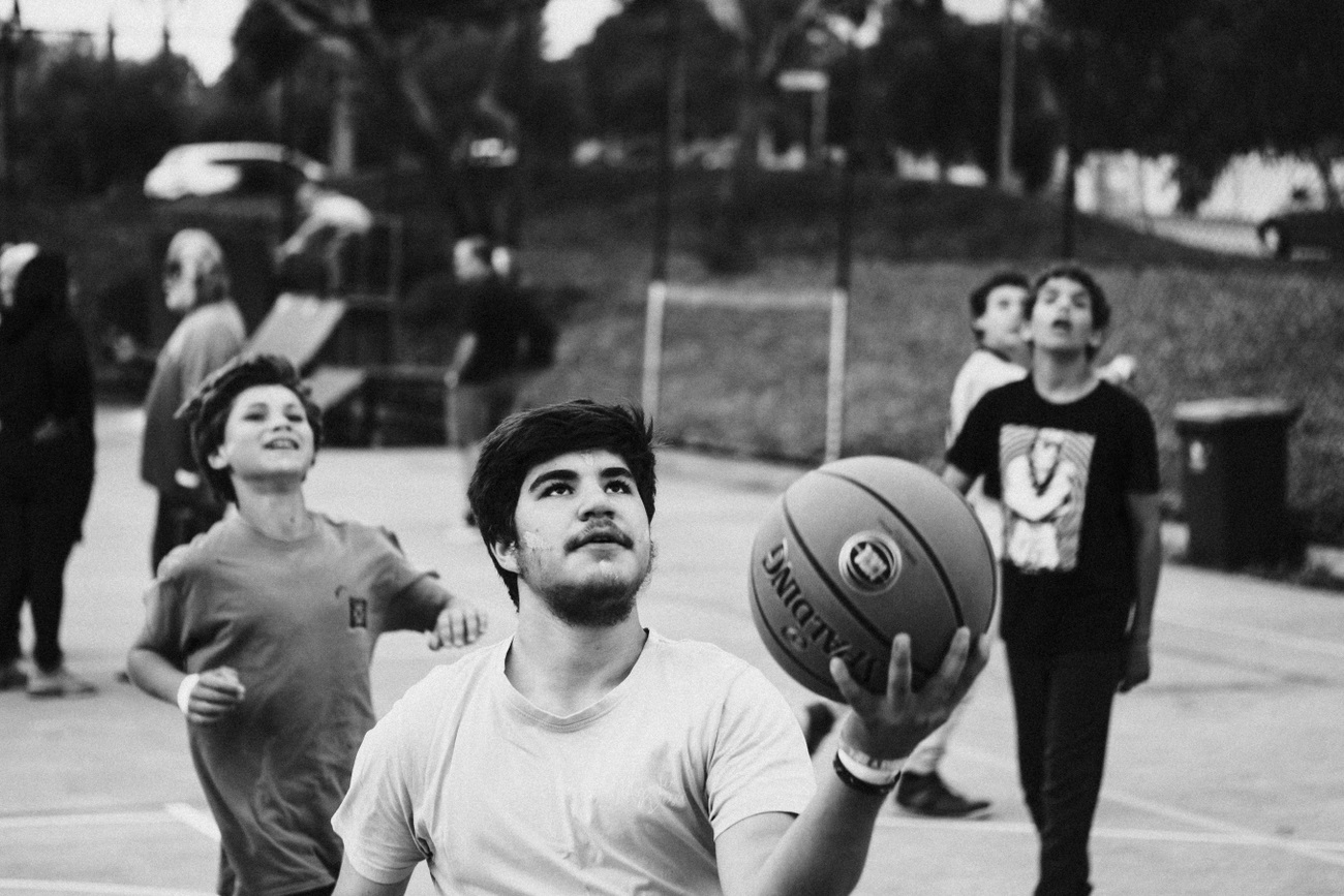 A group of young people in black and white play basketball.