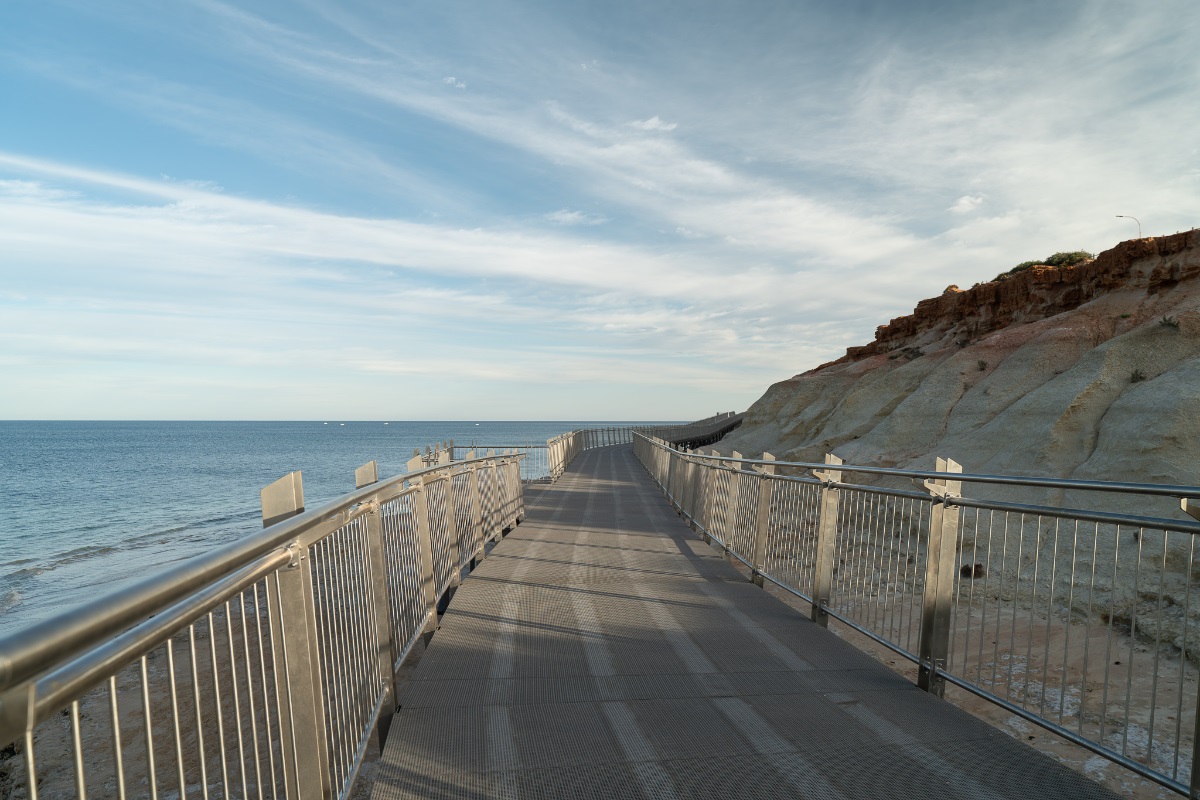 A view from the new boardwalk at Witton Bluff with the ocean to the left and red cliff to the right. Metal railings line the boardwalk.