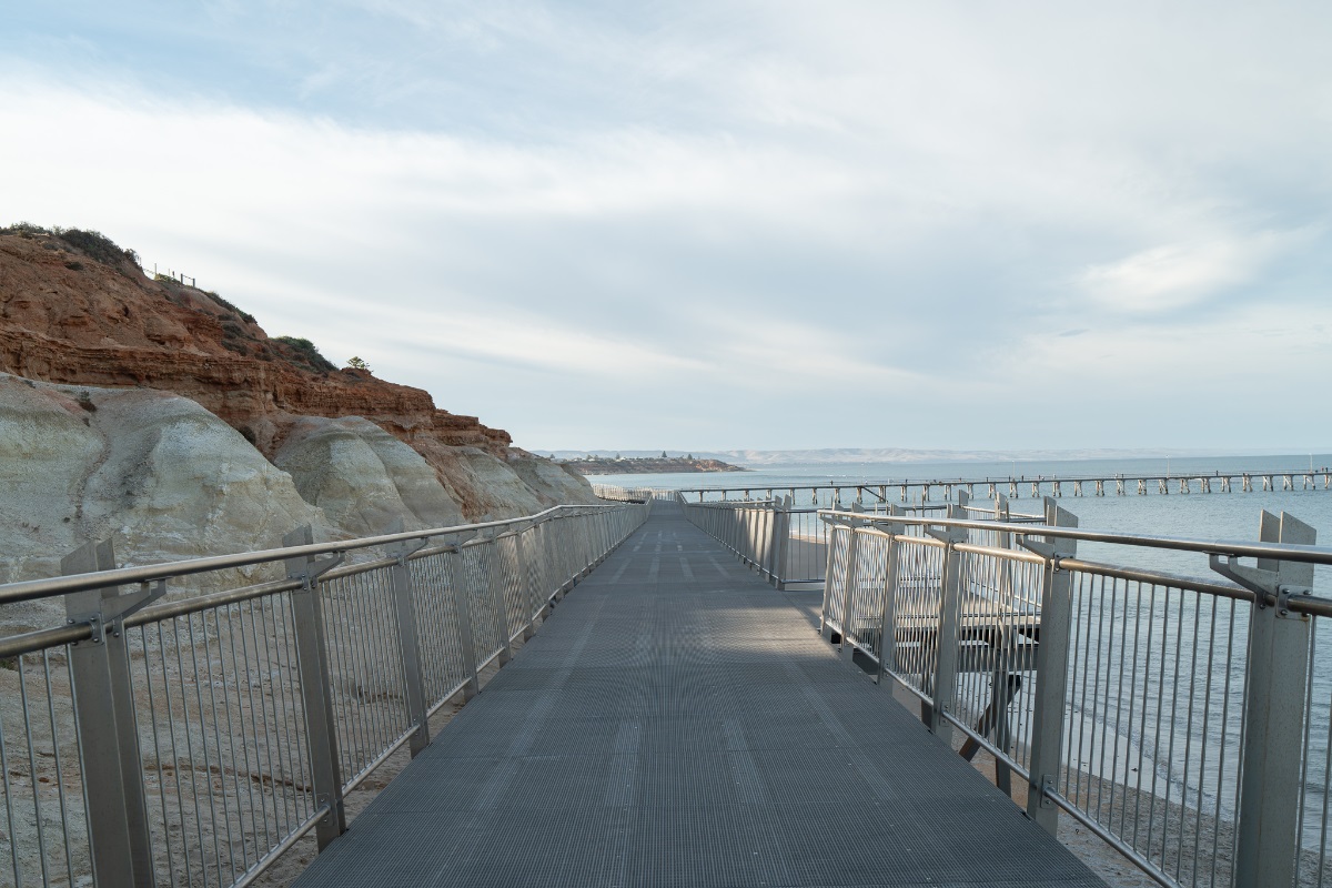 A view from the new boardwalk at Witton Bluff with the ocean to the left and red cliff to the right. Metal railings line the boardwalk.