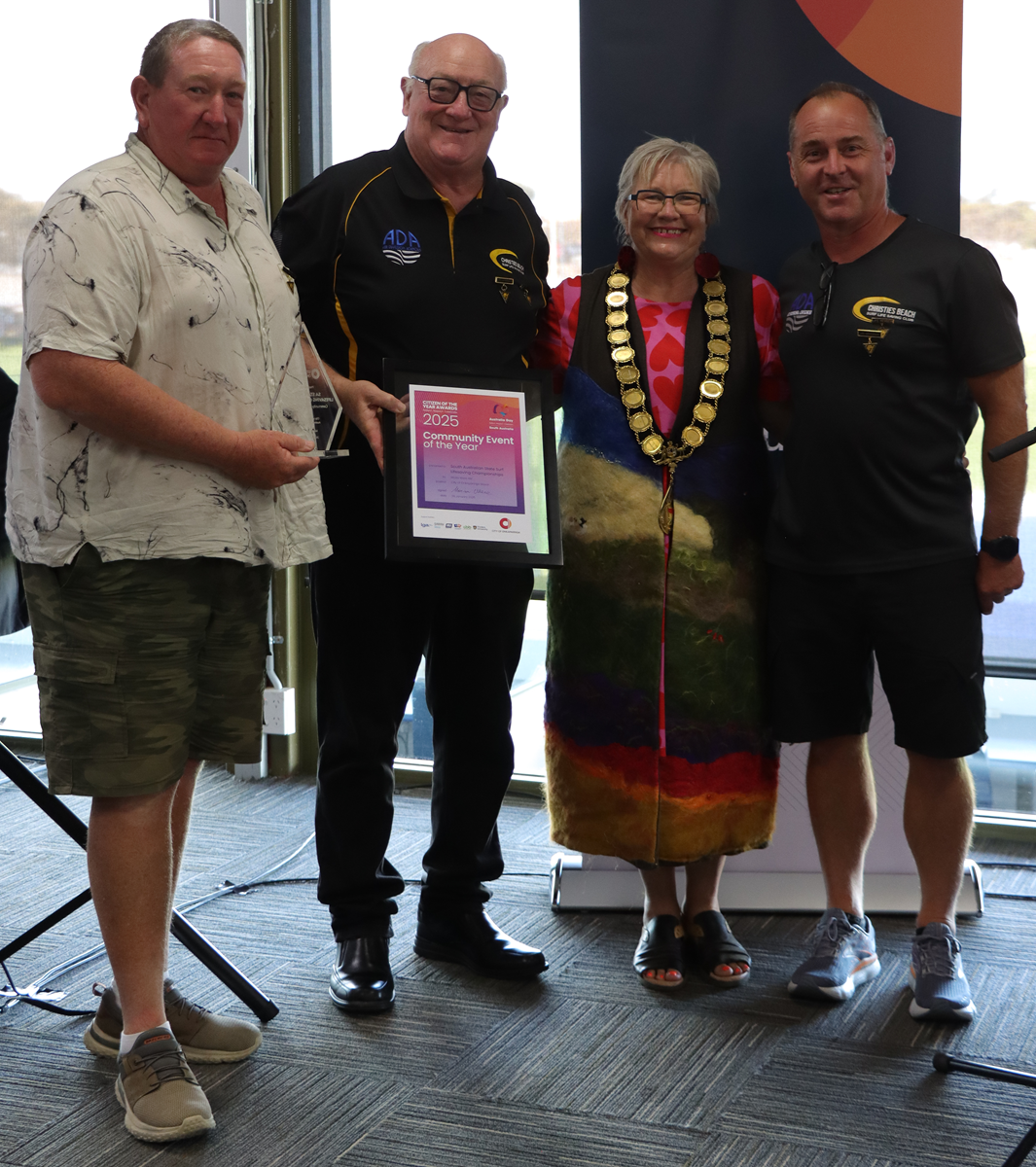 A photo of City of Onkaparinga Event of the Year recipients from the Christies Beach Surf Lifesaving Club with their framed award alongside Mayor Moira Were.