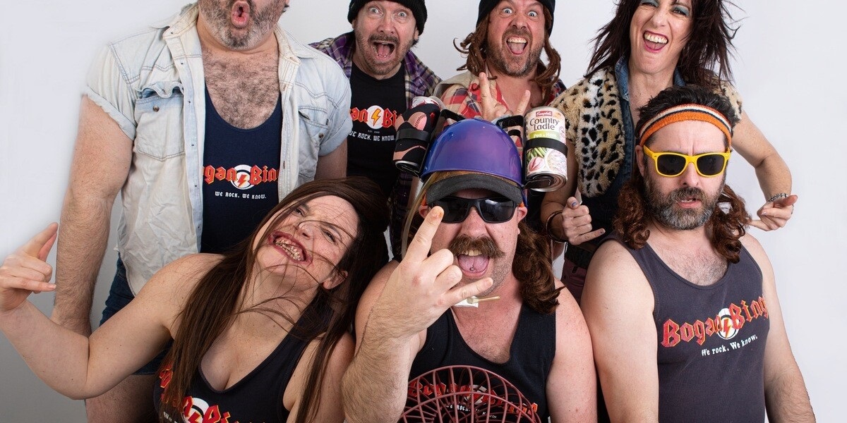 A group of seven 'bogans' wearing singlets and pulling funny faces at the camera.