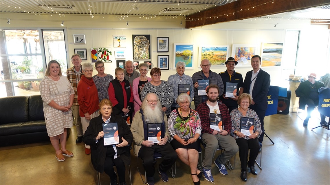 A large group of Onkaparinga Council volunteers smile with their recognition of service certificates.