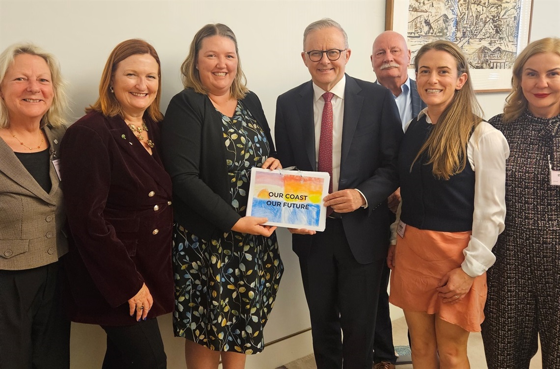 South Australian elected members smile alongside Prime Minister Anthony Albanese holding a colourful document with the title, 'Our coast our future
