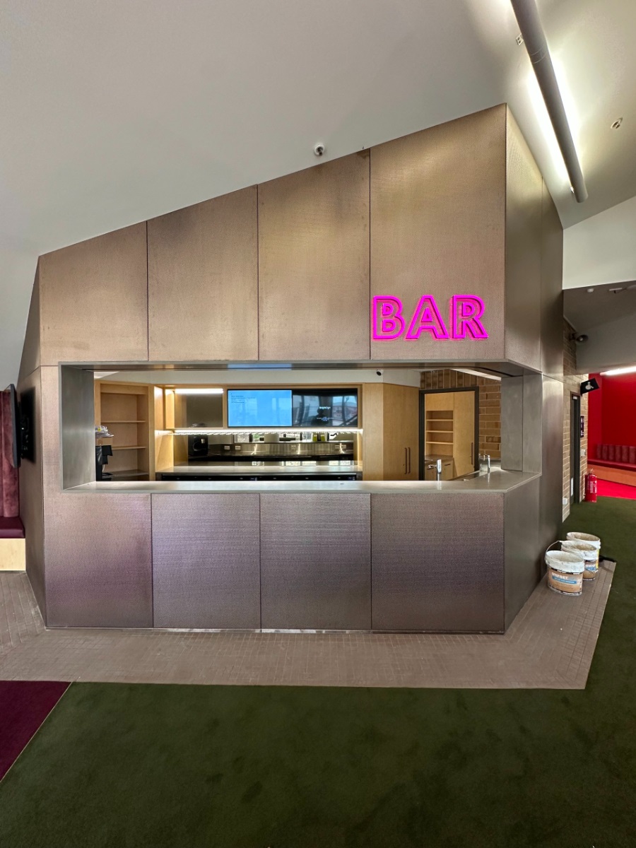 A view of the metallic exterior of the upgraded Hopgood Theatre bar, with bright pink signage.