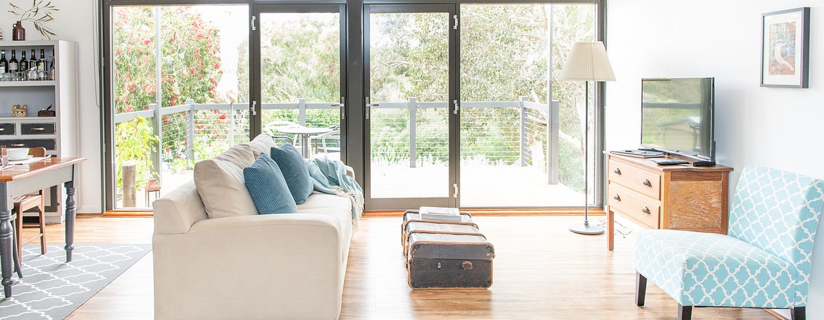 The tastefully decorated lounge room of Karawatha Cottages' Ponder Cottage, with sunligh streaming through the windows.