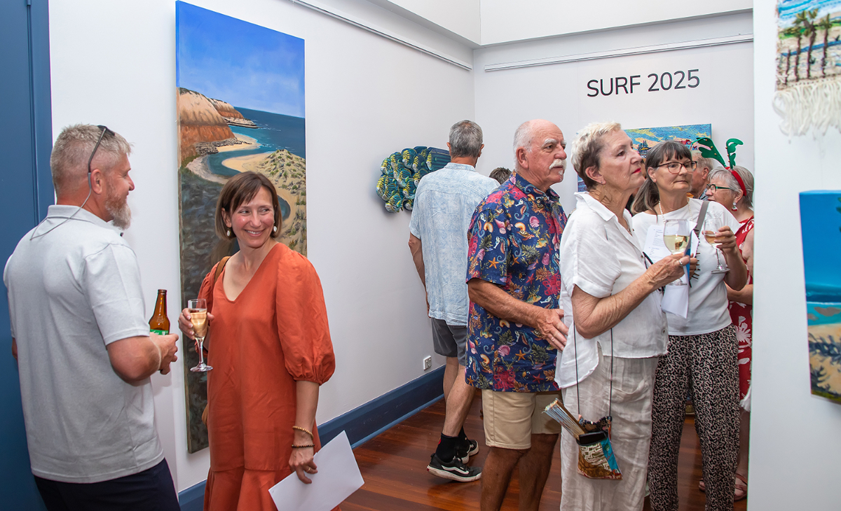 A group of people enjoy the surf art exhibition at the Arts Centre.