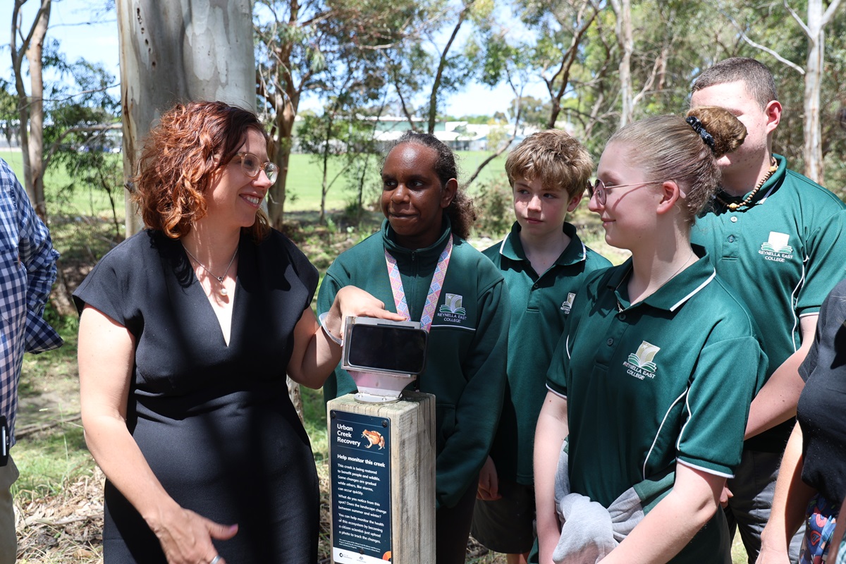 Amanda Rishworth MP smiles and stands alongside students from Reynella East College and a photo point location at an urban creek.