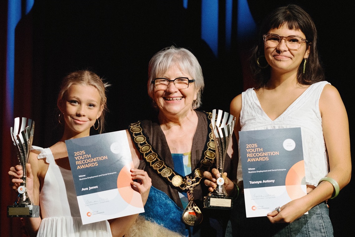City of Onkaparinga Mayor Moira Were stands in the middle of the joint 2025 Youth Recognition Award winners for Business, Employment and Social Enterprise on a stage with their certificates.